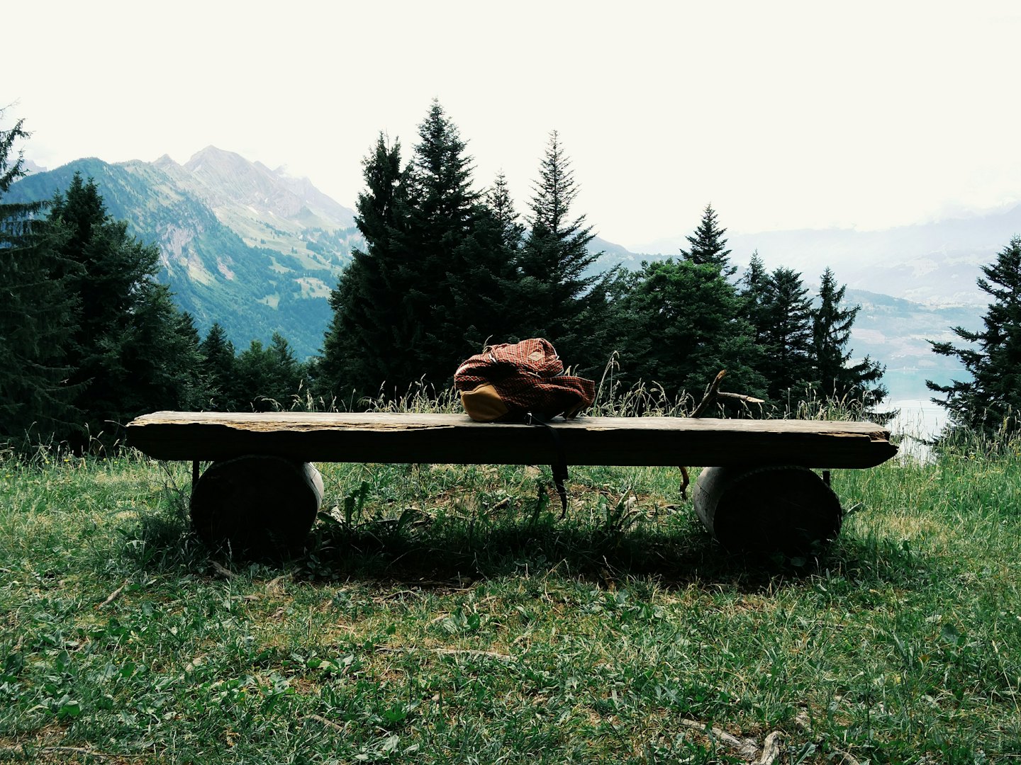 Rustic log bench with a folded sweater overlooking mountain peaks.